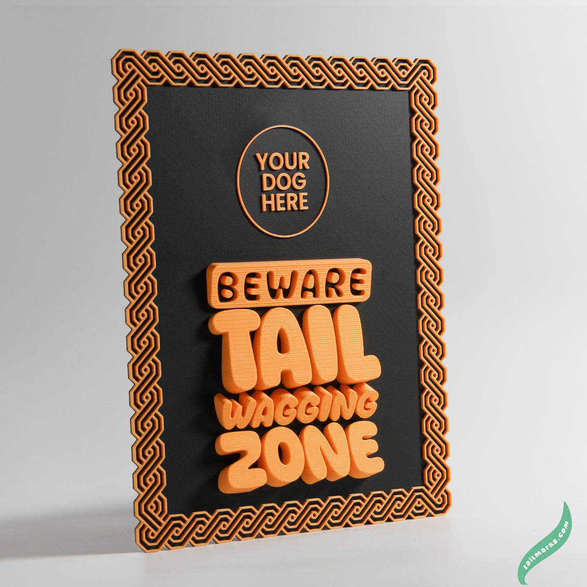 Decorative sign with orange text 'Your Dog Here Beware Tail Wagging Zone' on a black background and a maya frame